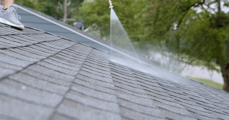 Close view of rejuvenation treatment being sprayed evenly across gray asphalt shingles